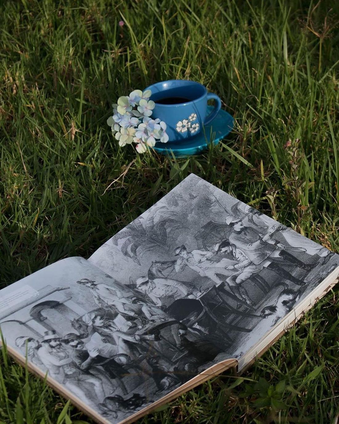 A cup of Hansa coffee beside a book of old Ceylon coffee-era engravings