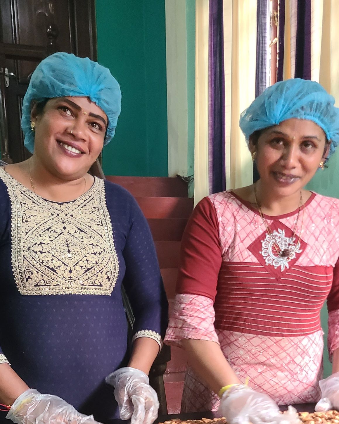 Kumari and Pushpa smiling at the sorting table