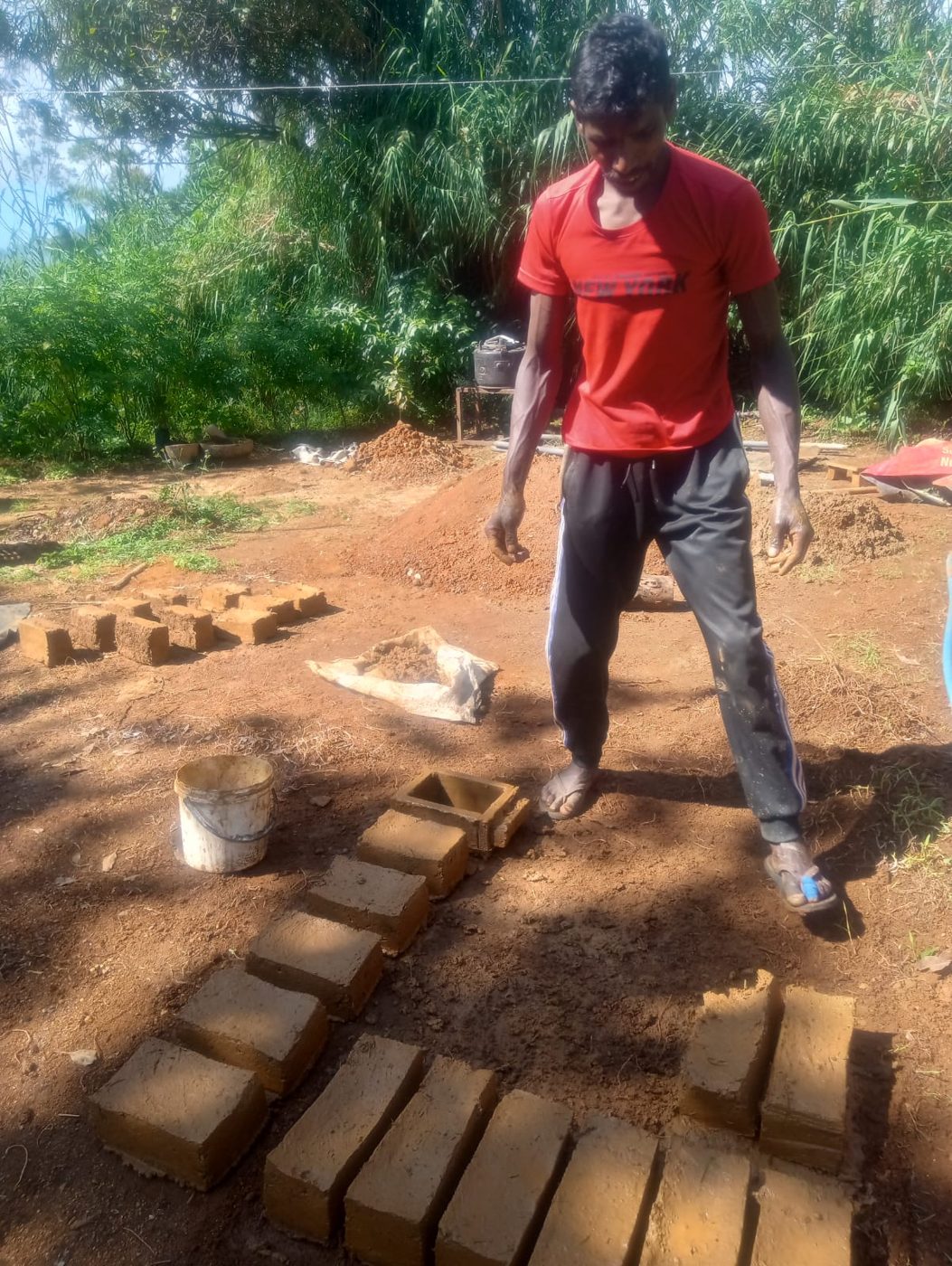 Murthi standing over rows of freshly moulded adobe bricks